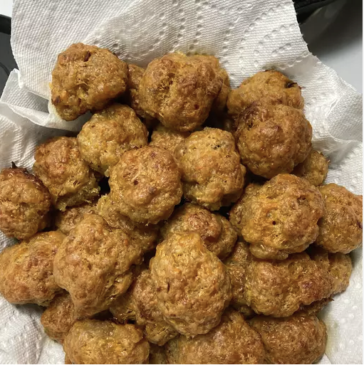 Homemade sausage balls on a plate with dipping sauces, garnished with fresh parsley.