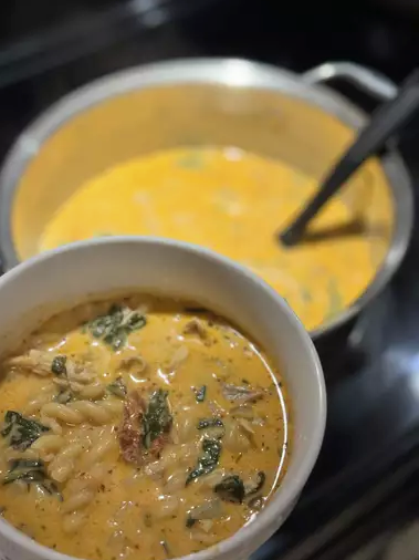 A bowl of creamy Marry Me Chicken Soup garnished with fresh basil, served with crusty bread