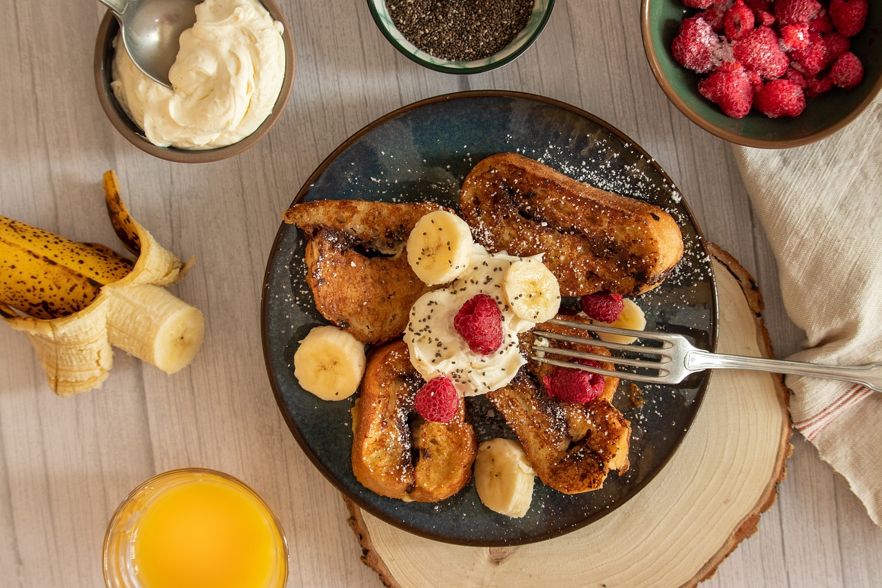 Golden slices of sourdough French toast topped with fresh berries, a drizzle of maple syrup, and a sprinkle of powdered sugar.