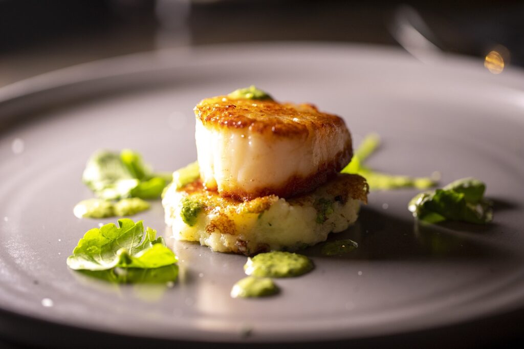 Galician-style scallops baked with breadcrumbs, onions, and parsley on a white plate